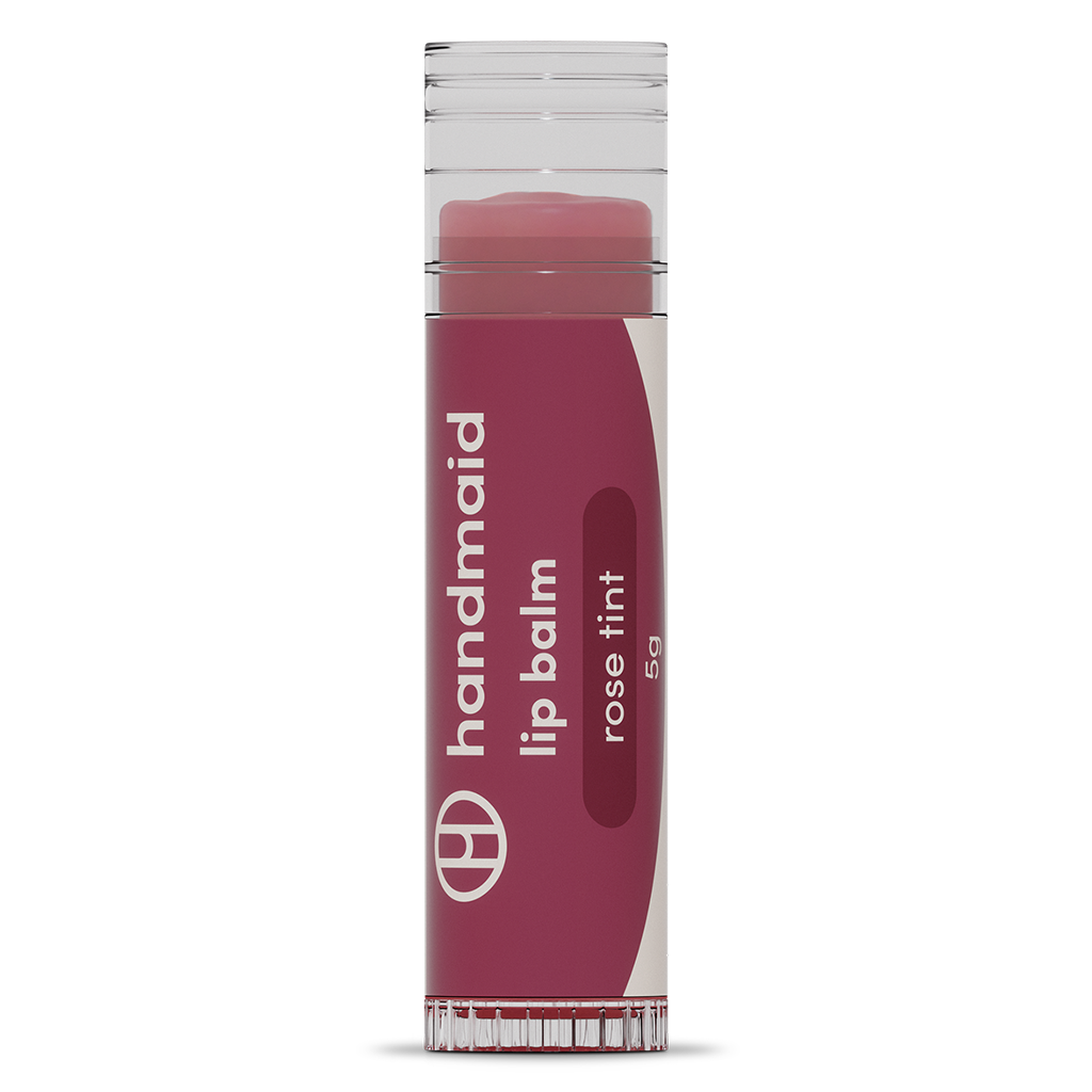 A tube of handmade lip balm with a rose tint, branded with 'handmaid - lip balm' in a rose pink color.